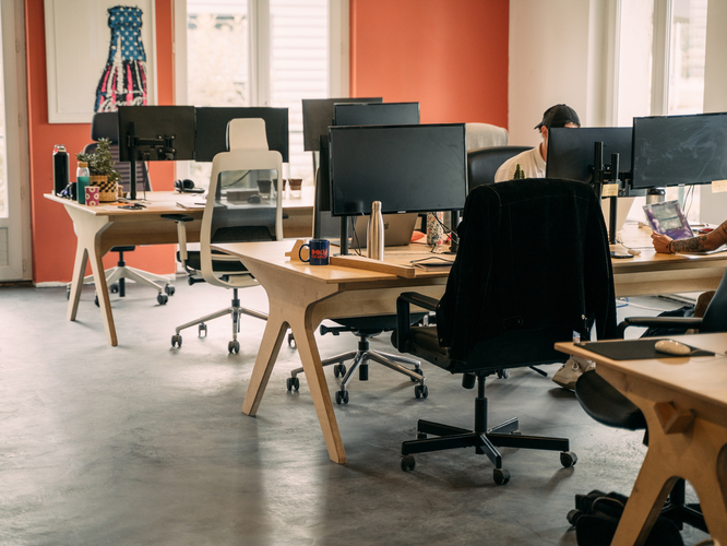 Espace de travail aménagé en open space avec du mobilier en bois de bouleau.