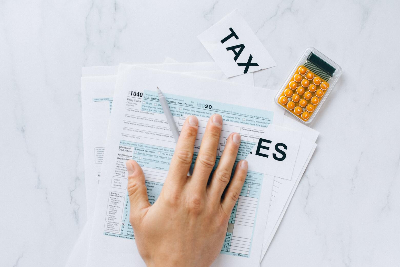Plusieurs documents sur les taxes sont posés sur une table ainsi qu'une calculatrice.