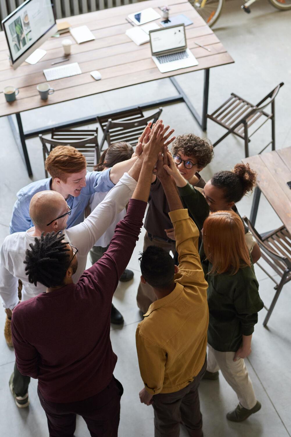 8 collaborateurs et collaboratrices sont en rond et se font un check en levant leur main vers le haut, comme pour montrer un engagement RSE.