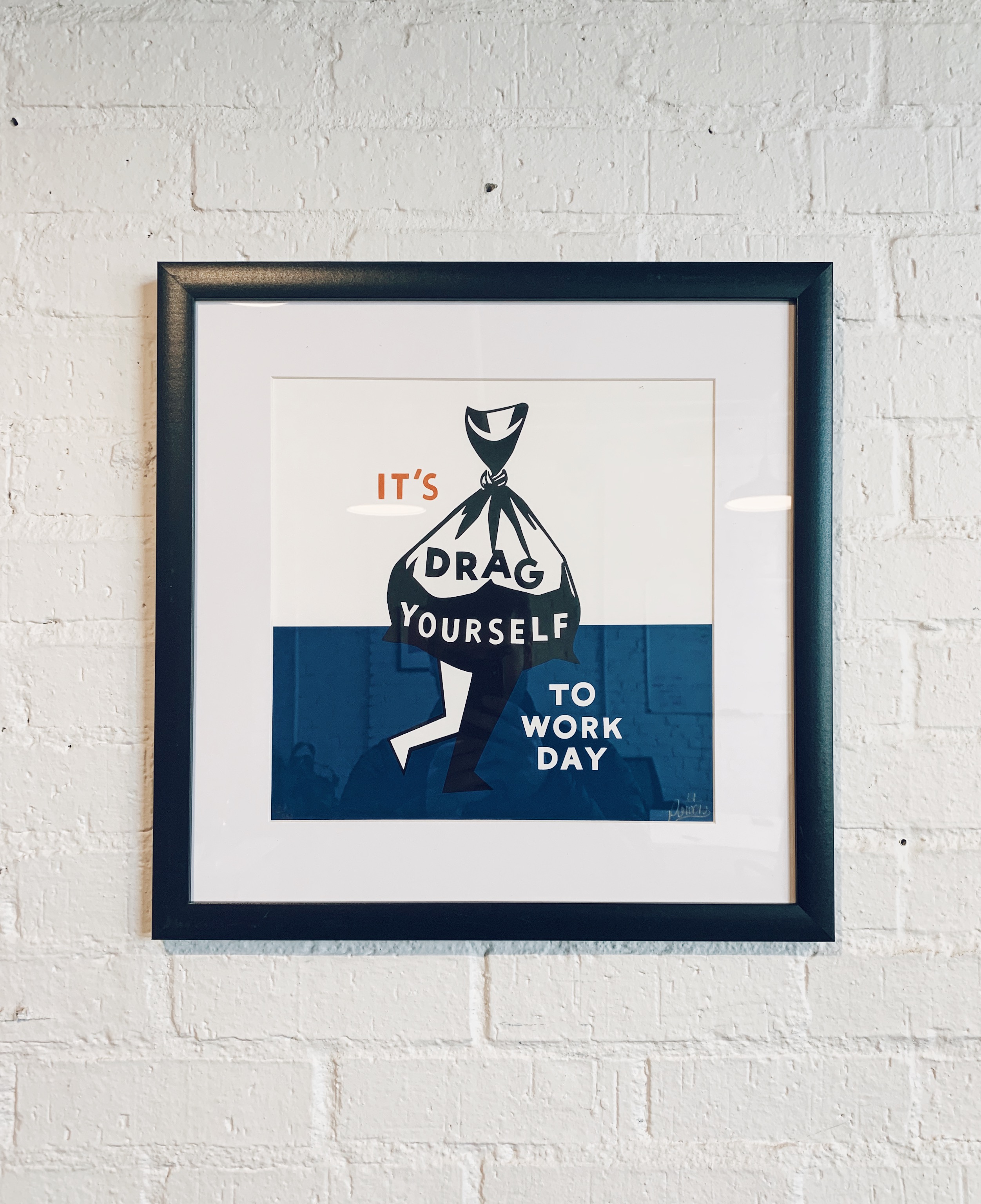 Painting on white brick wall that says (sarcastically), "It's drag yourself to work day"