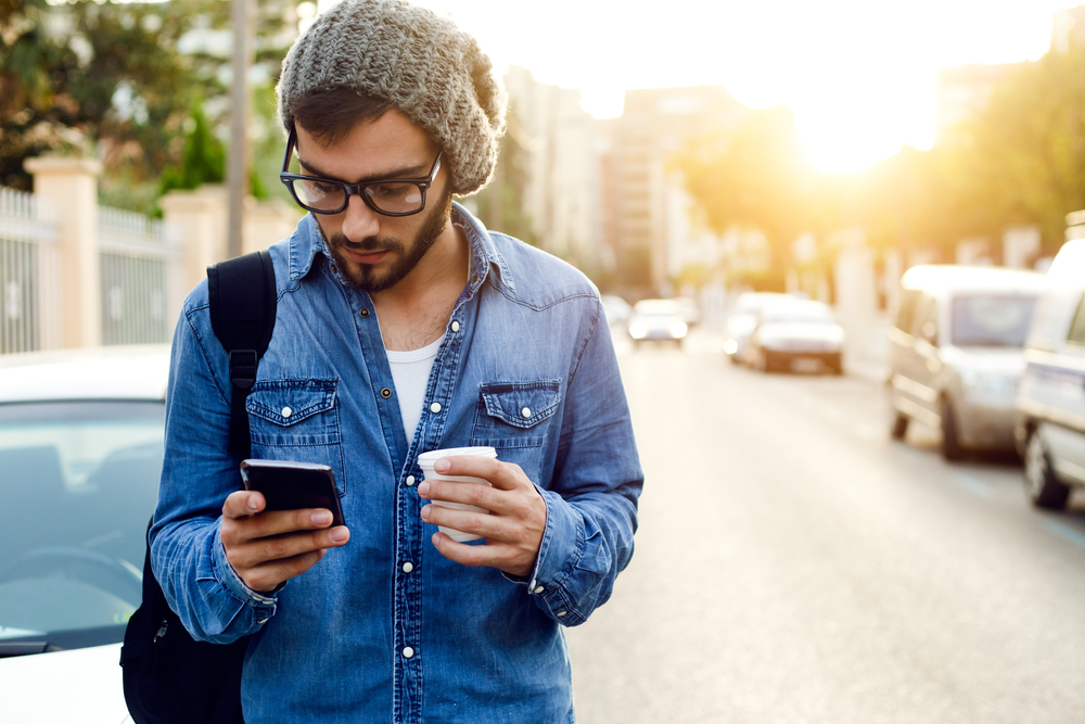 Trendy man checking phone outdoors