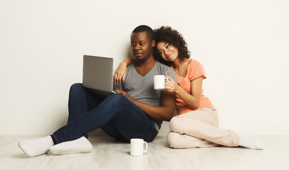 Happy african-american couple shopping for life insurance online on a laptop.