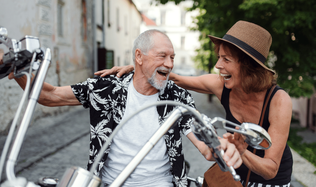 Cheerful Elderly Couple with Motorbike in Town