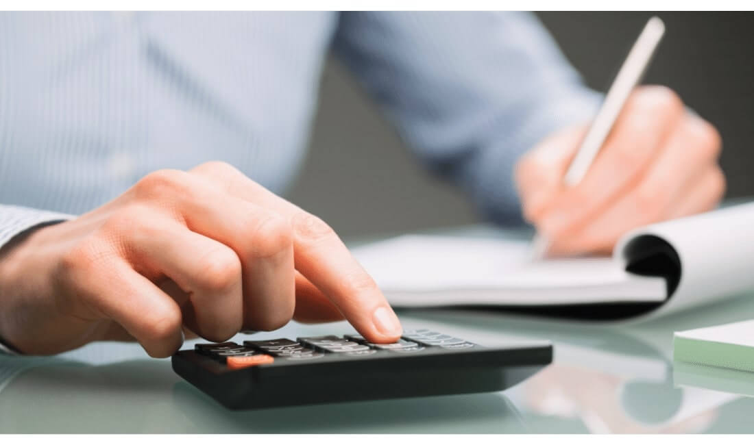 Man writing on notebook with calculator