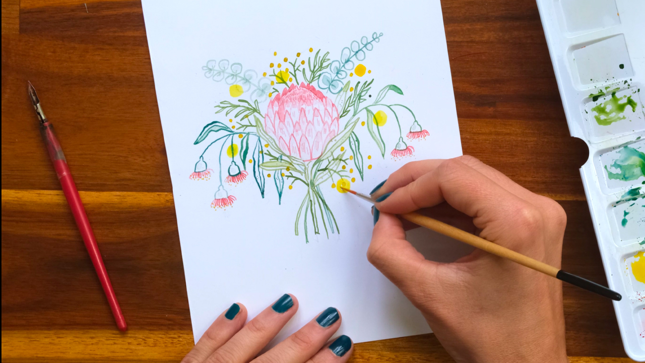 A top down photo of an artist painting Australian native flowers