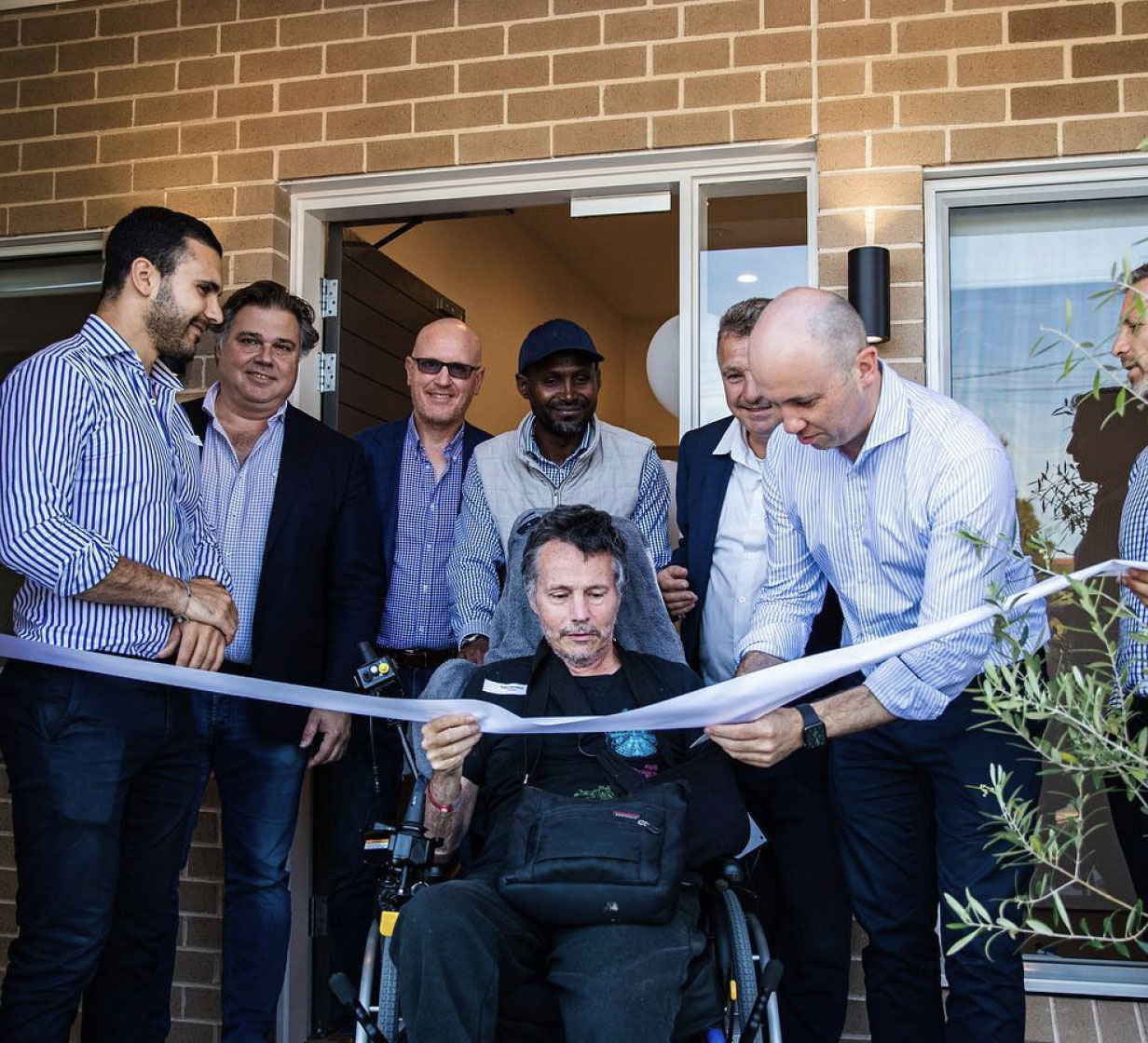 A resident cutting a ribbon on the opening day of their new home