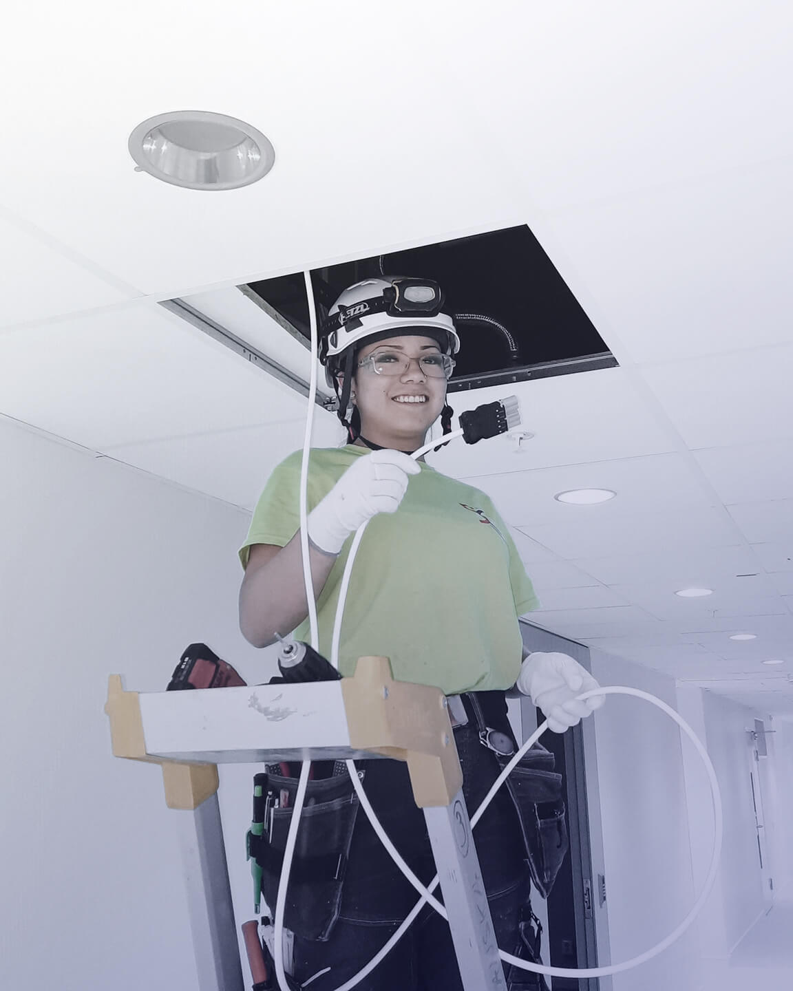 Ung kvinna står på stege och håller i el-kabel