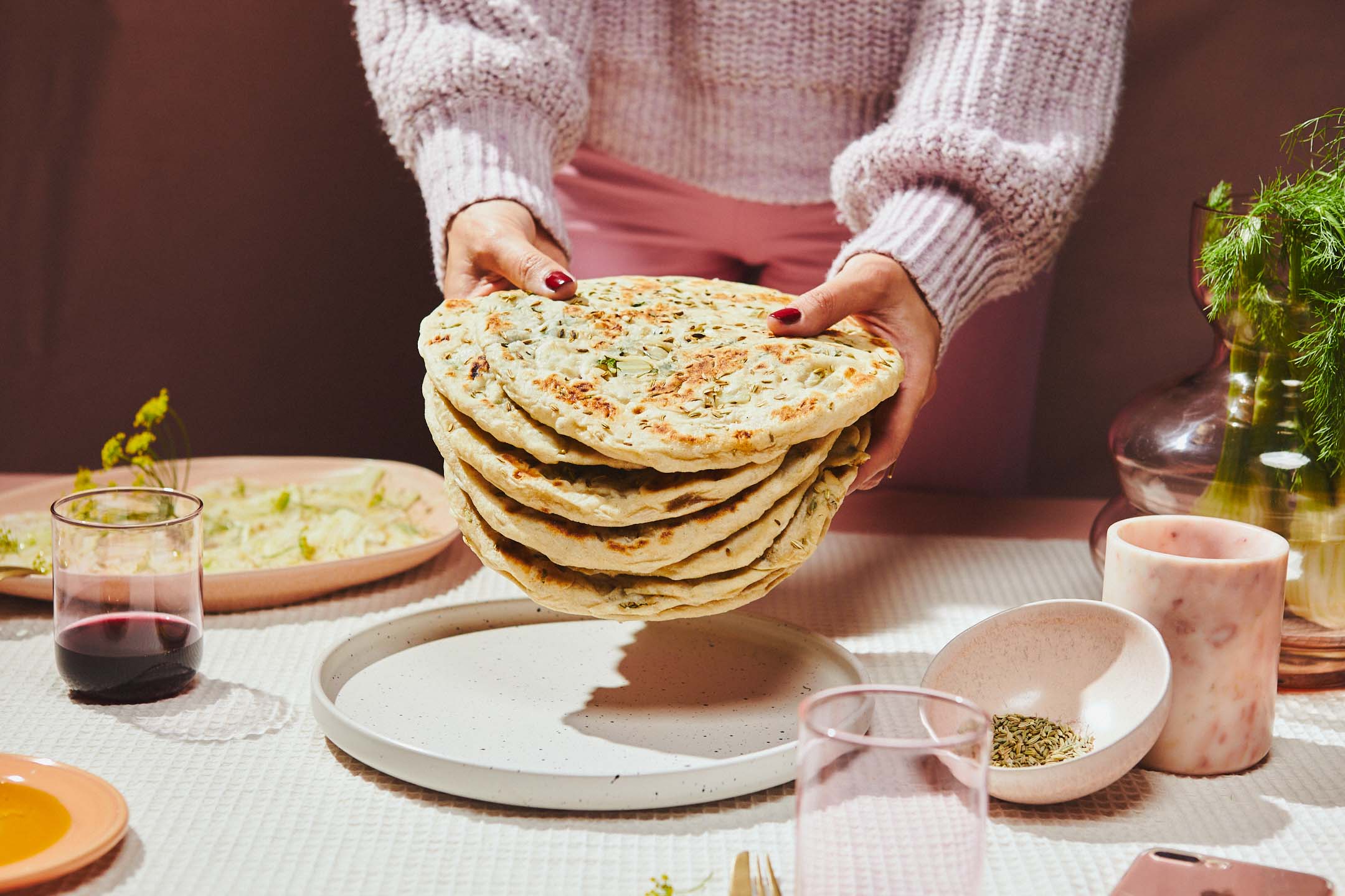 hand reaching for a cup of coffee next to a pastry on a bright lime green background.
