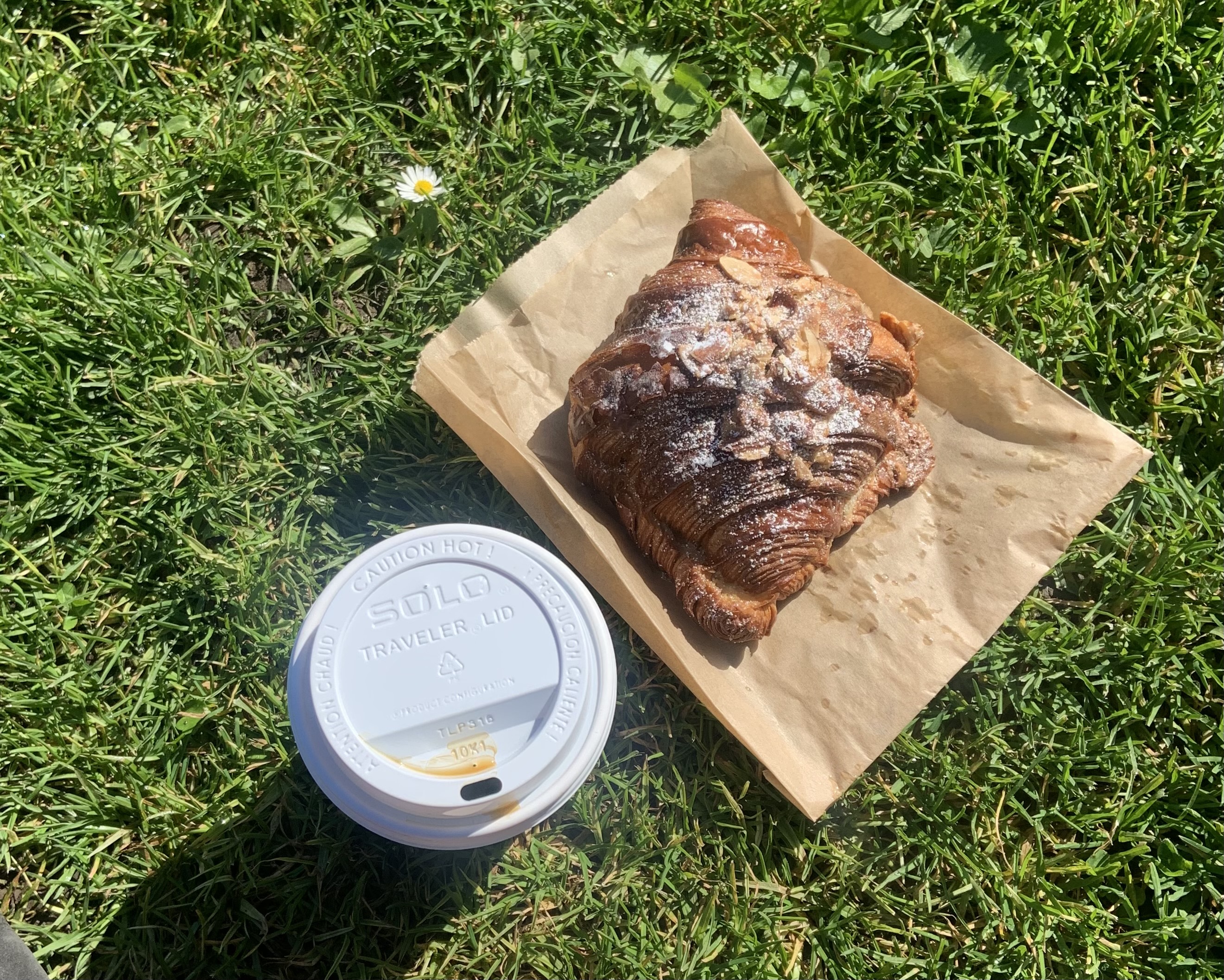 hand reaching for a cup of coffee and cardamom bun