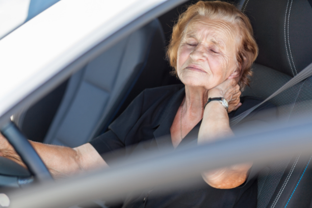 women in car holding her neck