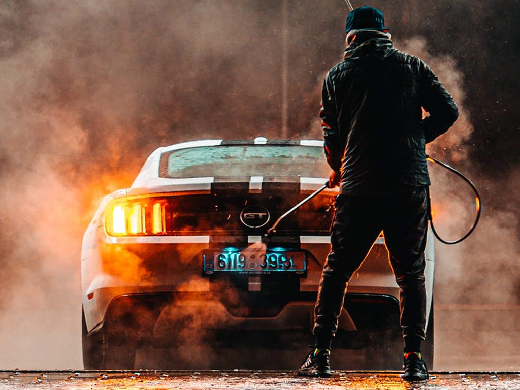 Image of man pressure washing his car