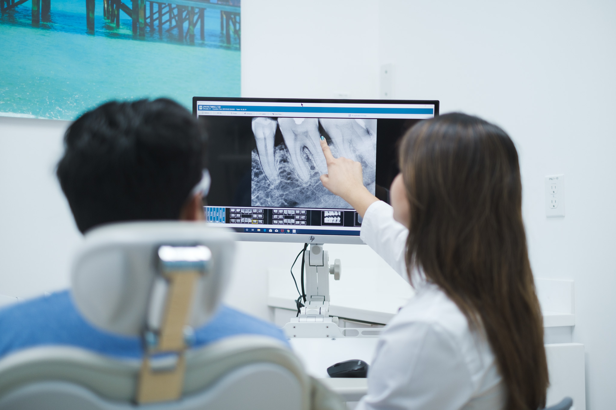Doctor at Trident Smiles Dental talking to a patient and pointing towards an X-ray scan on a computer screen