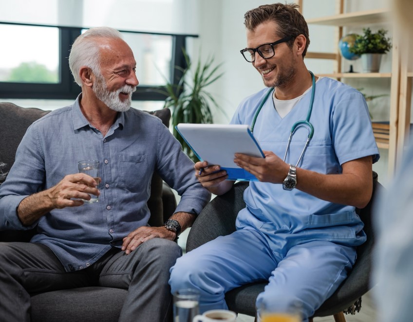 older man during his podiatry consultation laughing with his concimed doctor
