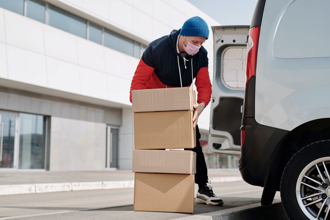 Delivery person wearing a mask and carrying boxes