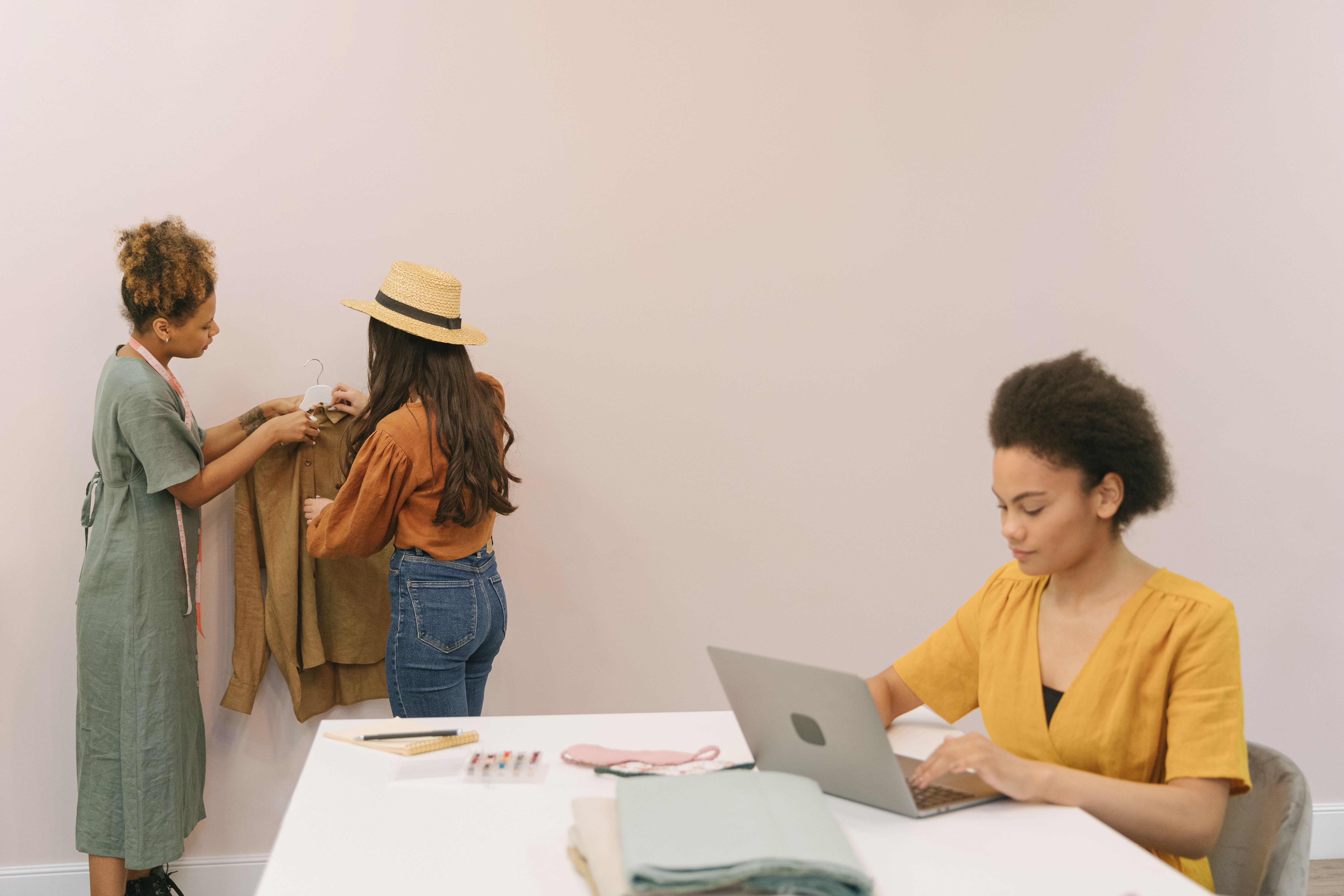 one woman using a computer and two women looking at clothes
