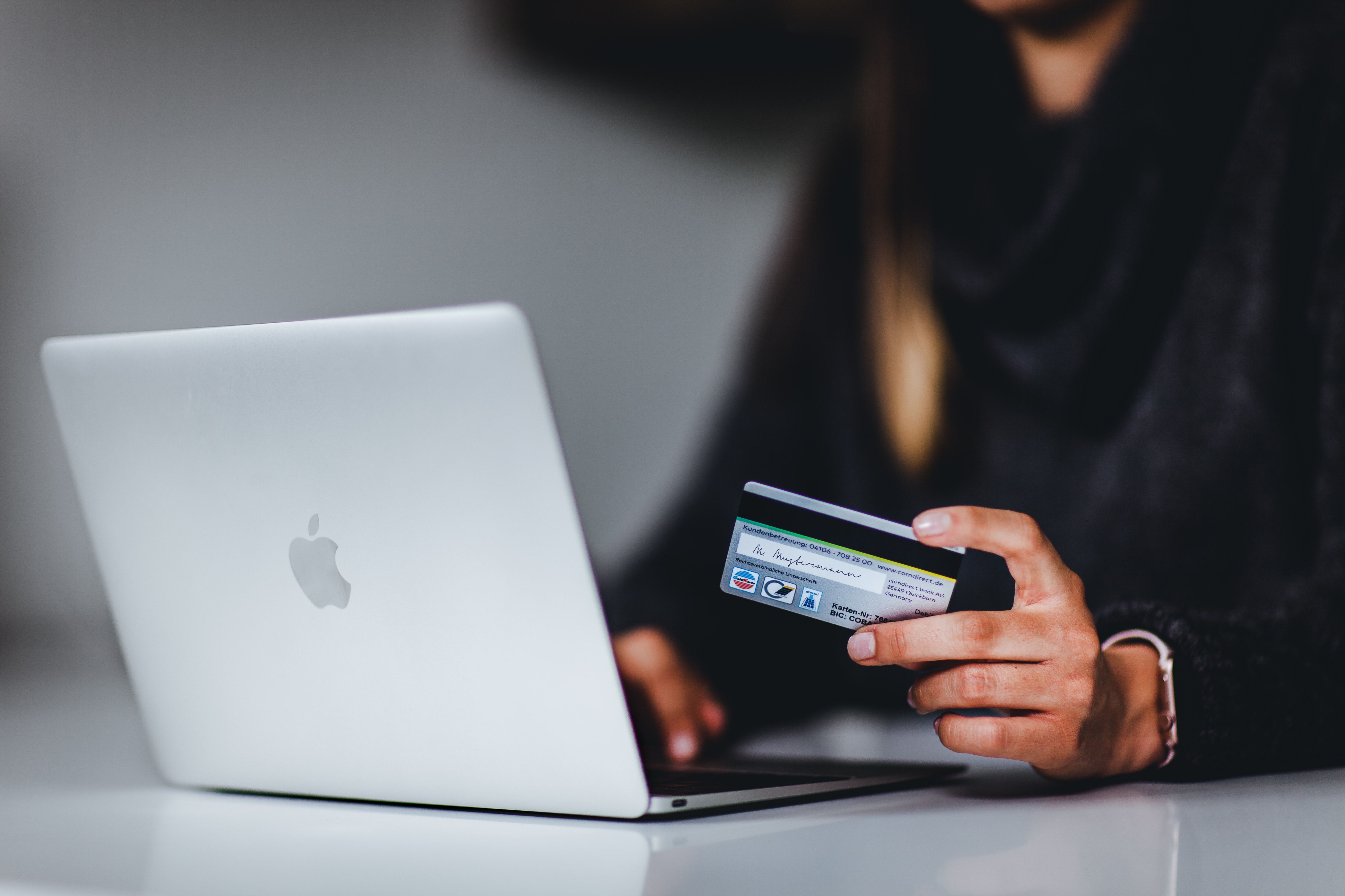 Woman holding a credit card and using a macbook