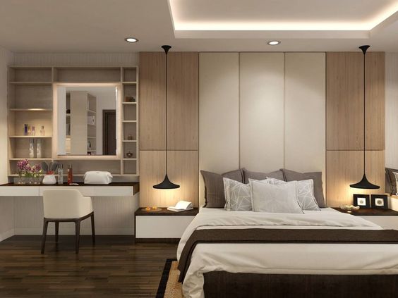 Hình ảnh toàn cảnh phòng ngủ với giường nệm êm ái, tab đầu giường nhỏ gọn, bộ đôi đèn thả màu đen, cạnh đó là bàn trang điểm với kệ mở gắn tường
