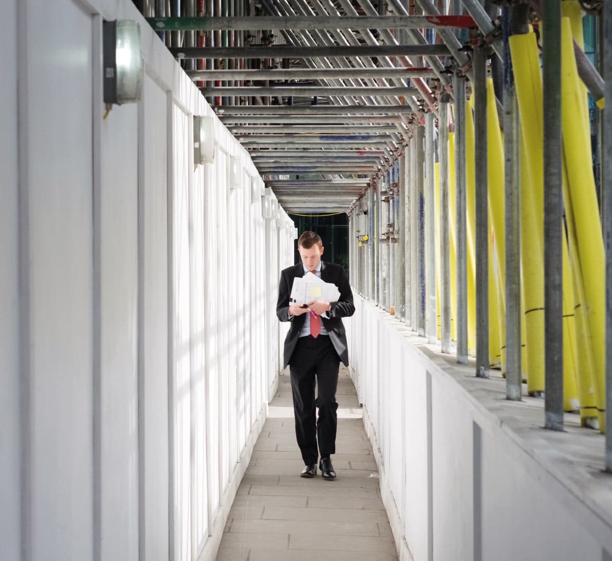 A man wearing a suit walks in a building site