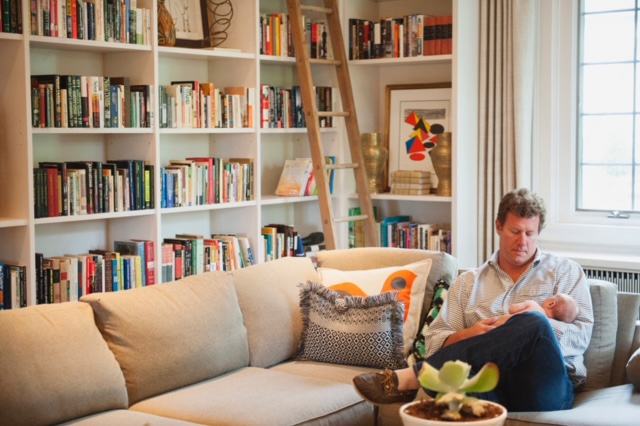 A man sitting on the sofa while holding a baby