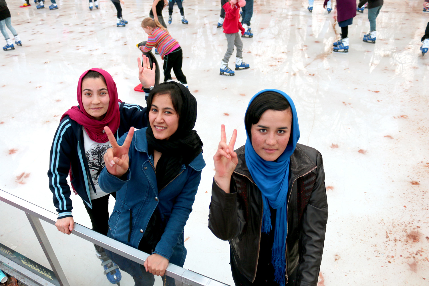Girls giving the peace sign while ice skating
