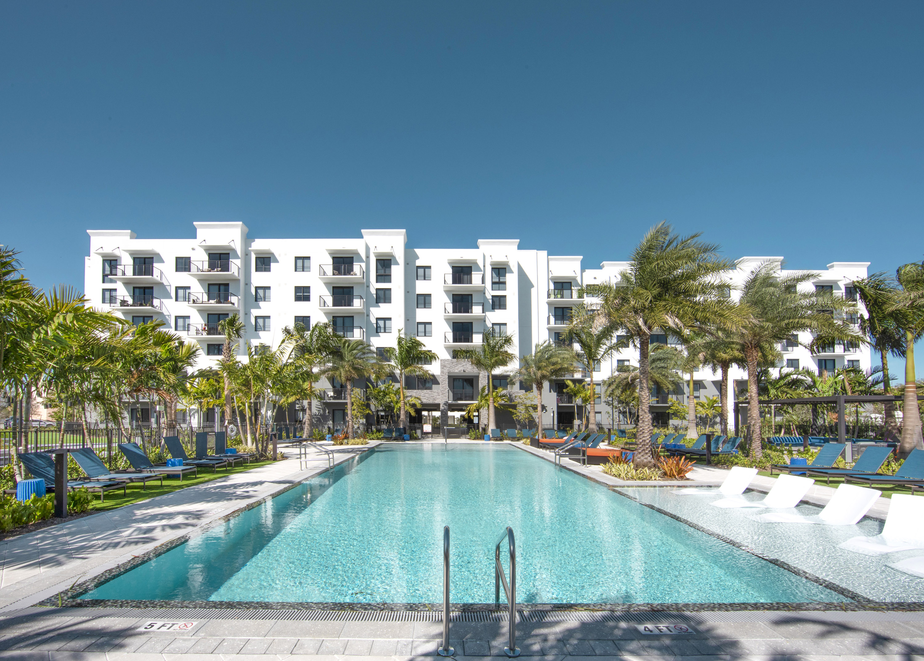 sanctuary pool surrounded by palm trees and Sanctuary Doral apartments behind