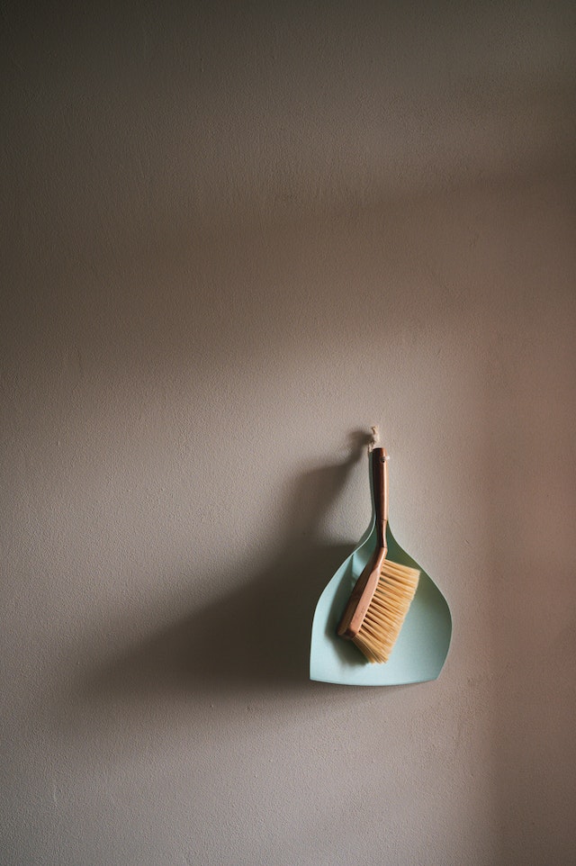 A small brown and dustpan on a wall