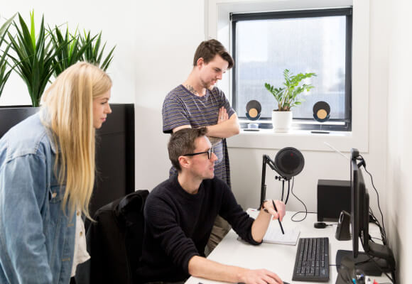 Three digital marketers standing and looking at a computer screen