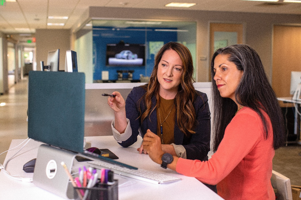 Two women working together in front of a laptop.