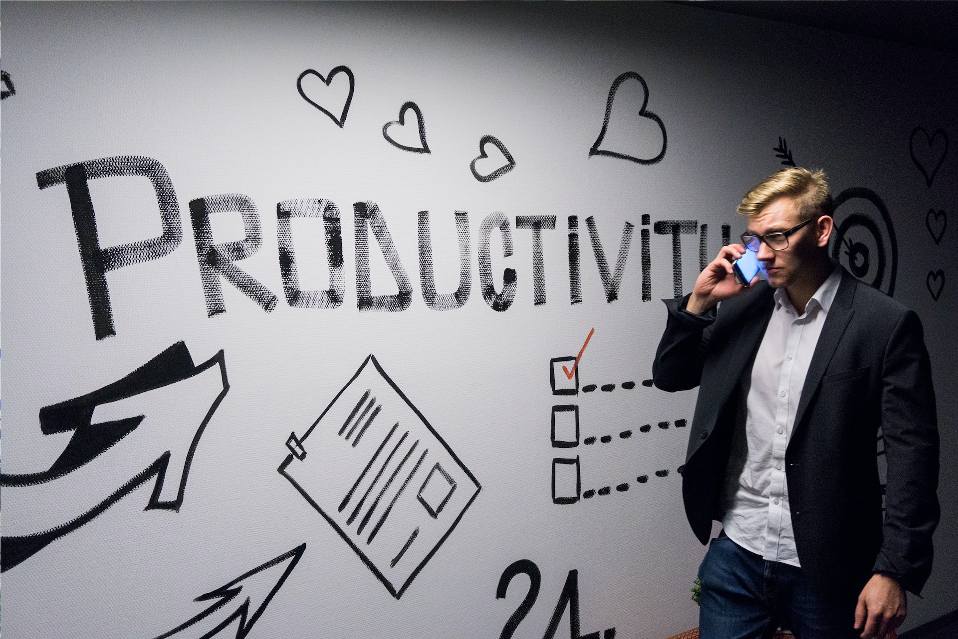 A man on his cellphone standing in front of a productivity board.