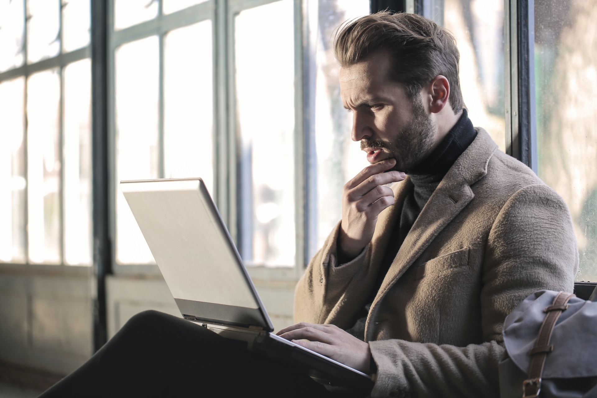 A man sitting with his laptop, deep in thought.