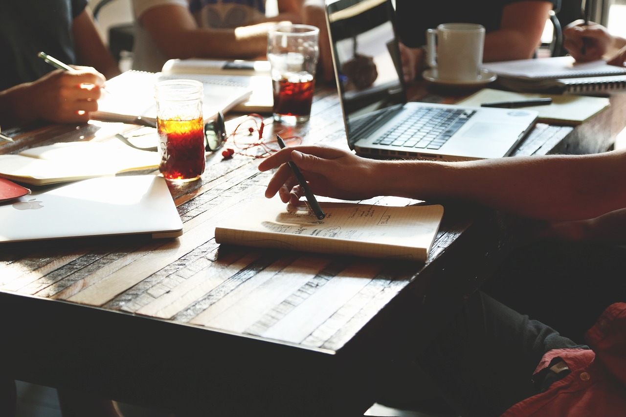 A team collaborating at a desk with laptops and notebooks.