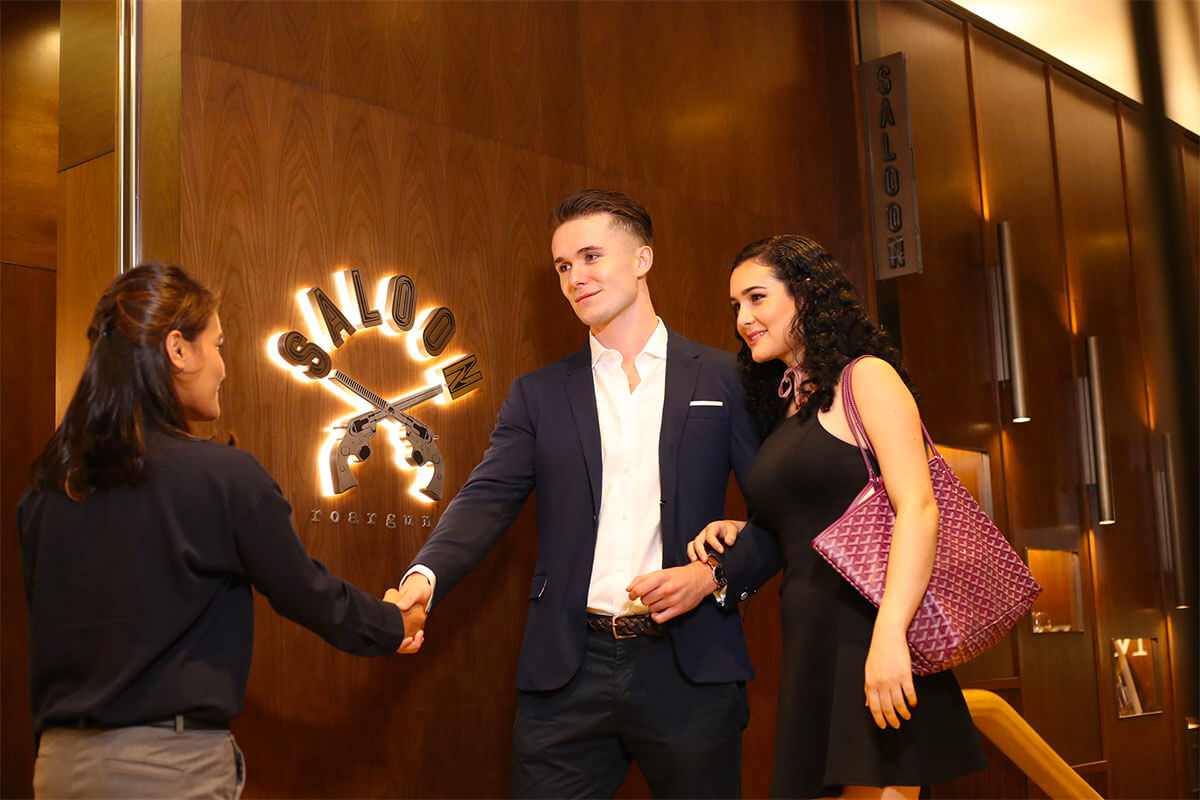 A Caucasian man and woman leaving Saloon Pacific Place in front of the store, shaking a staff's hand. The store logo is visible.
