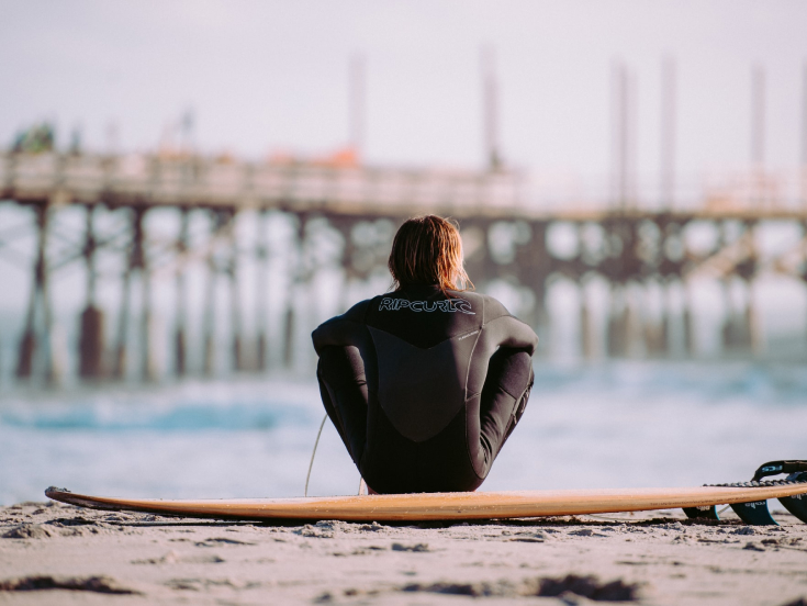 Man sitting on a surfboard looking over the sea