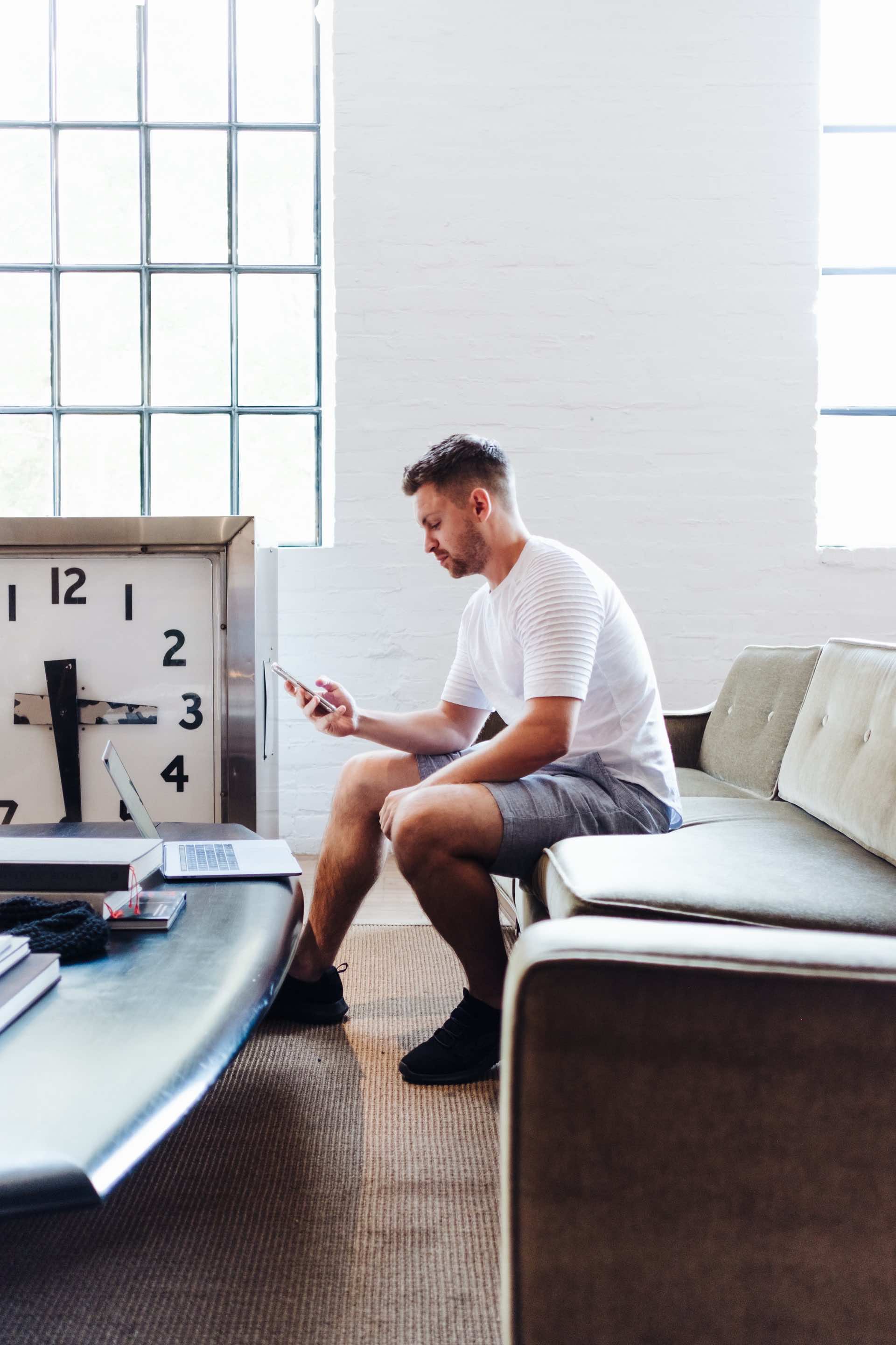 A white man in shorts on his phone