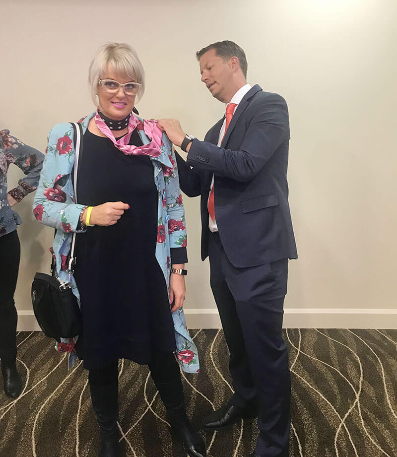 Vicki receiving a tie from JT Foxx, The world’s top wealth coach.
