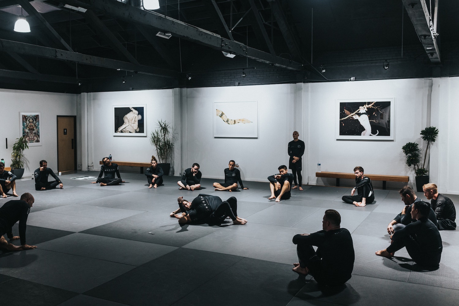 A group of people sat in a circle watching two people grappling