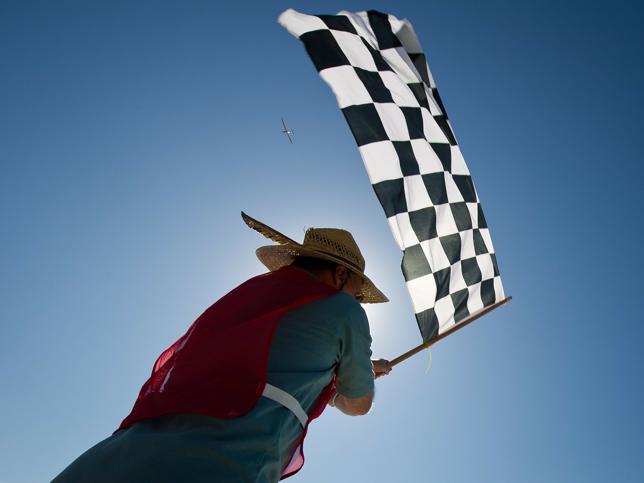 Eine Person schwenkt eine Zielflagge mit Schachbrettmuster