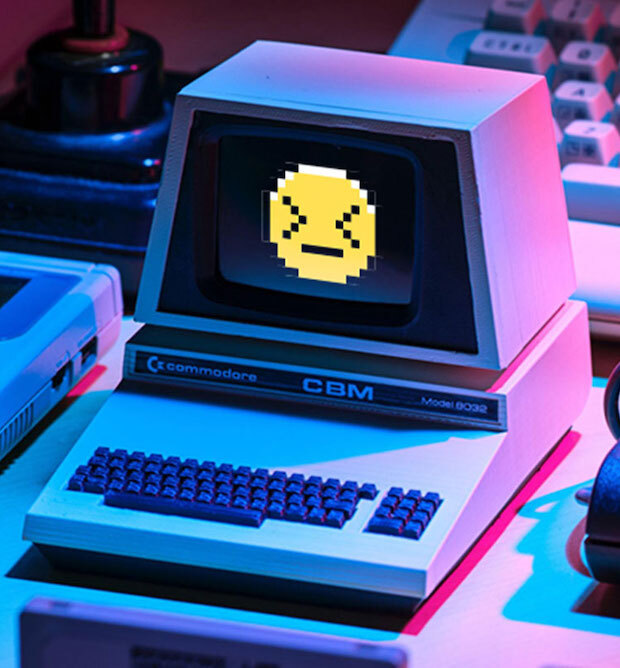 A retro looking computer with a digitized emoji on its screen