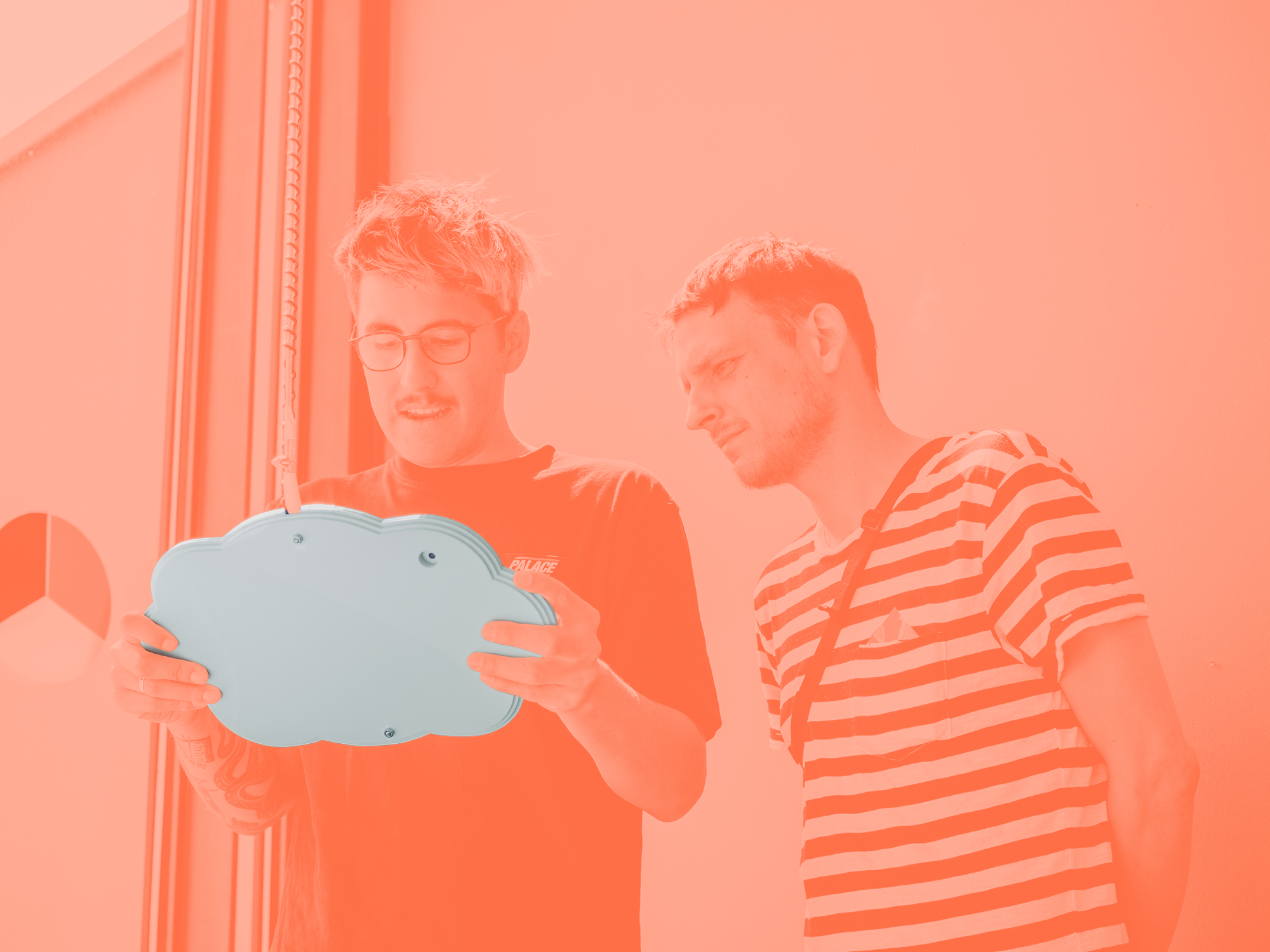 Two male students holding the cloud-shaped device and looking at the display with interest.