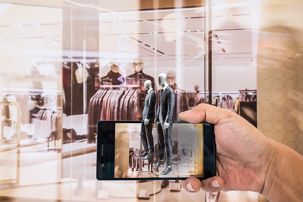 two digital avatars coming out of a smartphone sacanning a fashion store