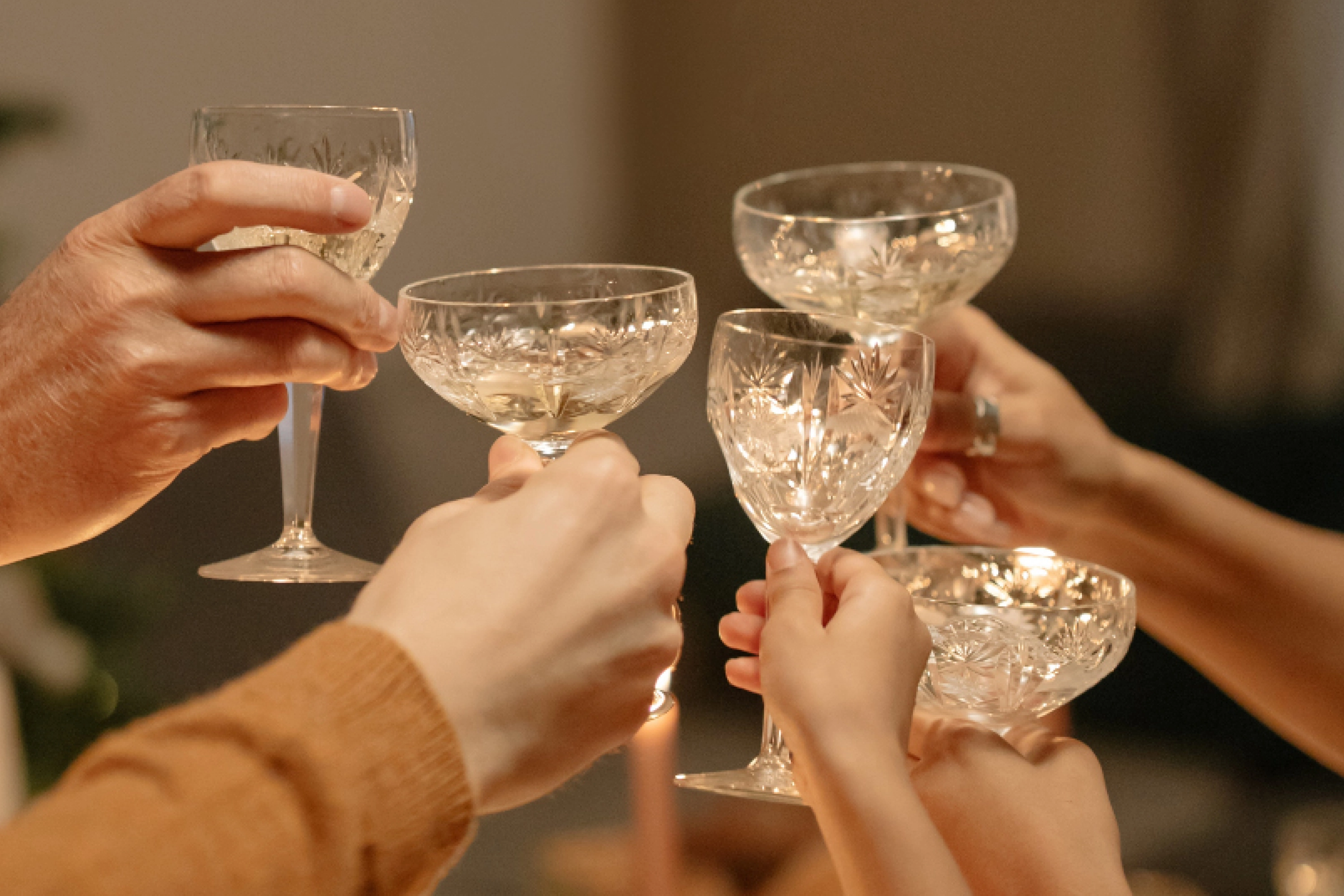five hands holding glasses to cheers
