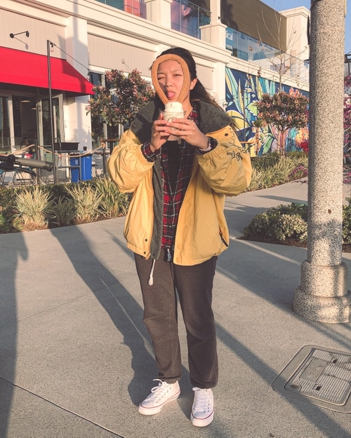 Tina sticking her tongue out and looking through a churro loop in ice cream.