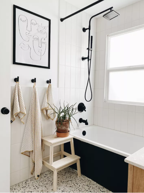 Secondary bathroom with black and white terrazzo flooring and black fixtures