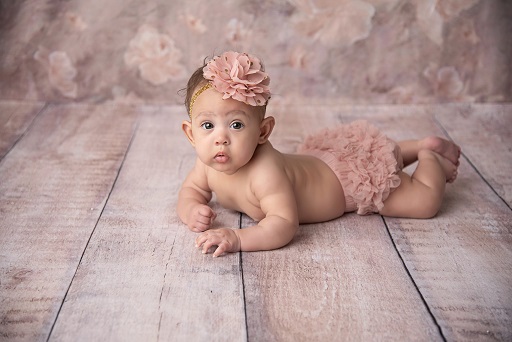 Photograph of newborn baby girl in pink flower outfit
