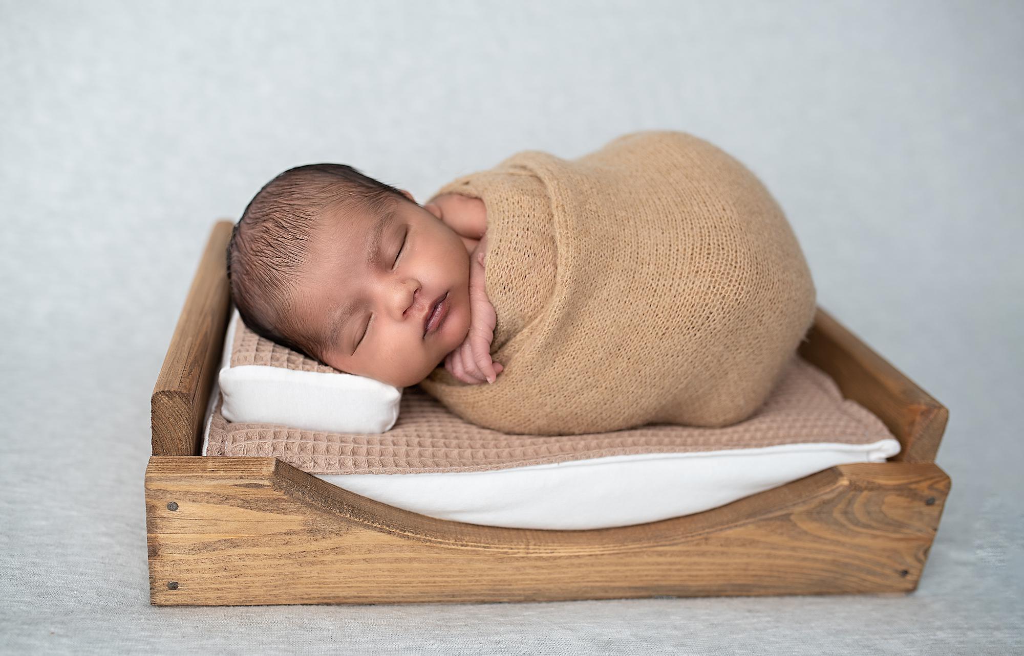 A newborn baby sleeping in a wooden bed