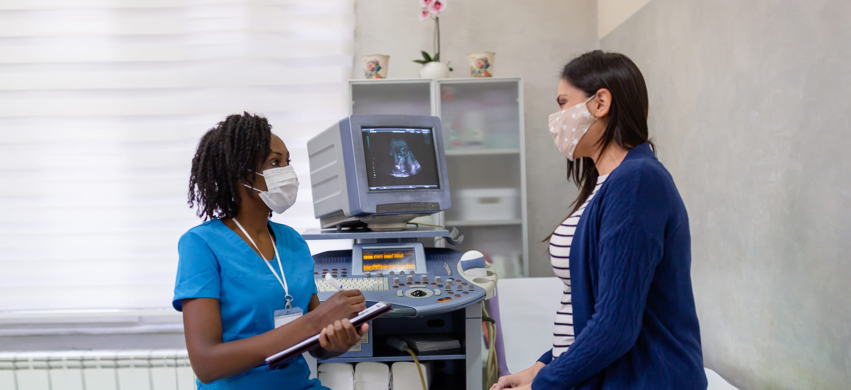 a nurse and patient consulting in a medical clinic, both with masks on