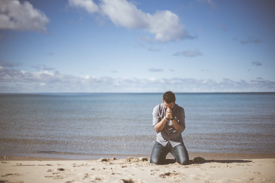 A man prays on a beach
