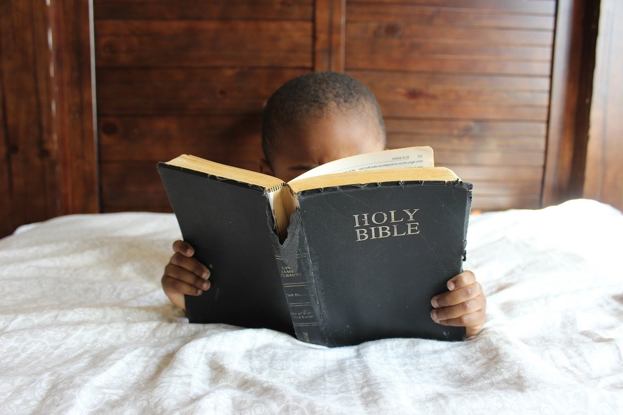 Child reading his Bible in bed