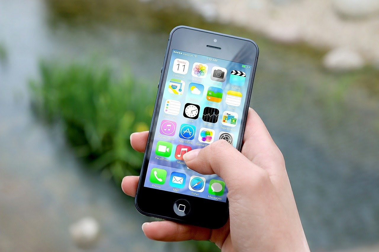 Person holding a phone with apps displayed.