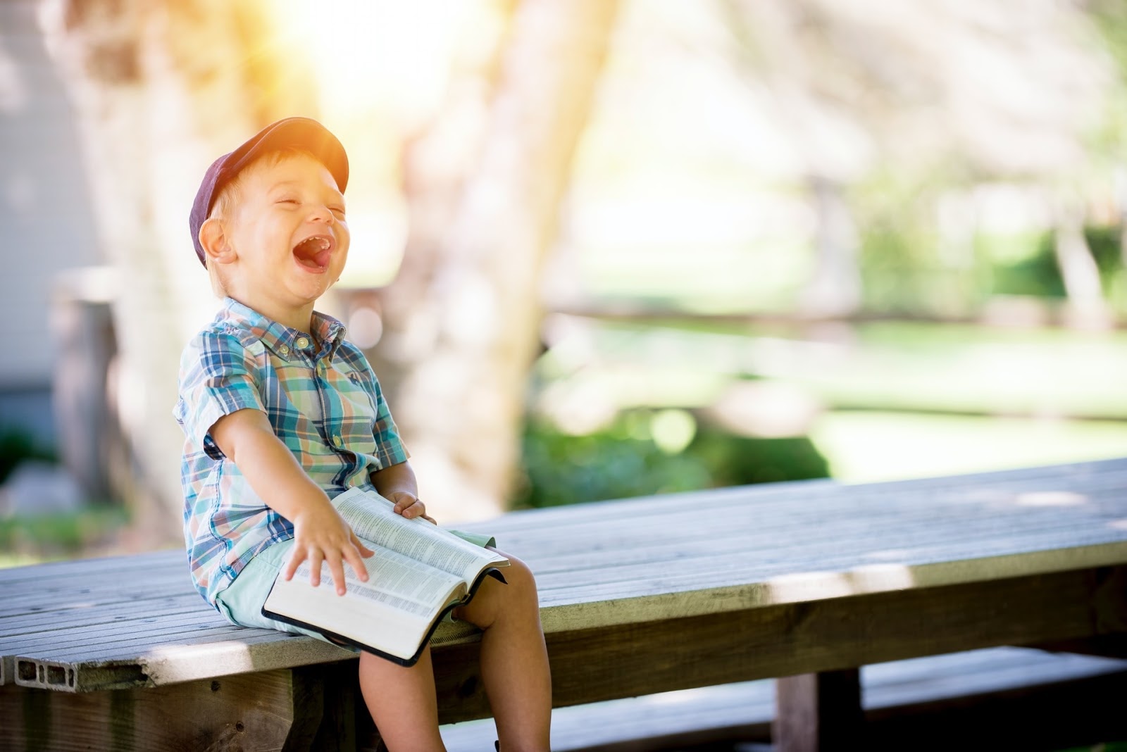 young boy laughing and sitting on a table with a bible